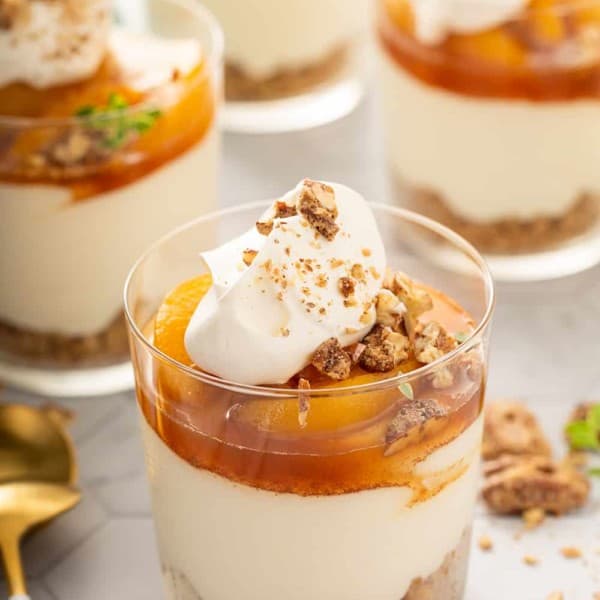 Four assembled peach peach cheesecakes on a white countertop