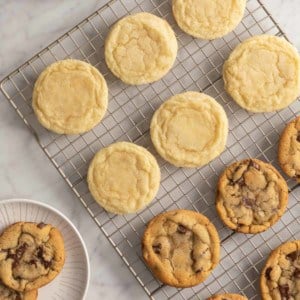 Assorted perfectly round sugar cookies and chocolate chip cookies on a wire cooling rack.