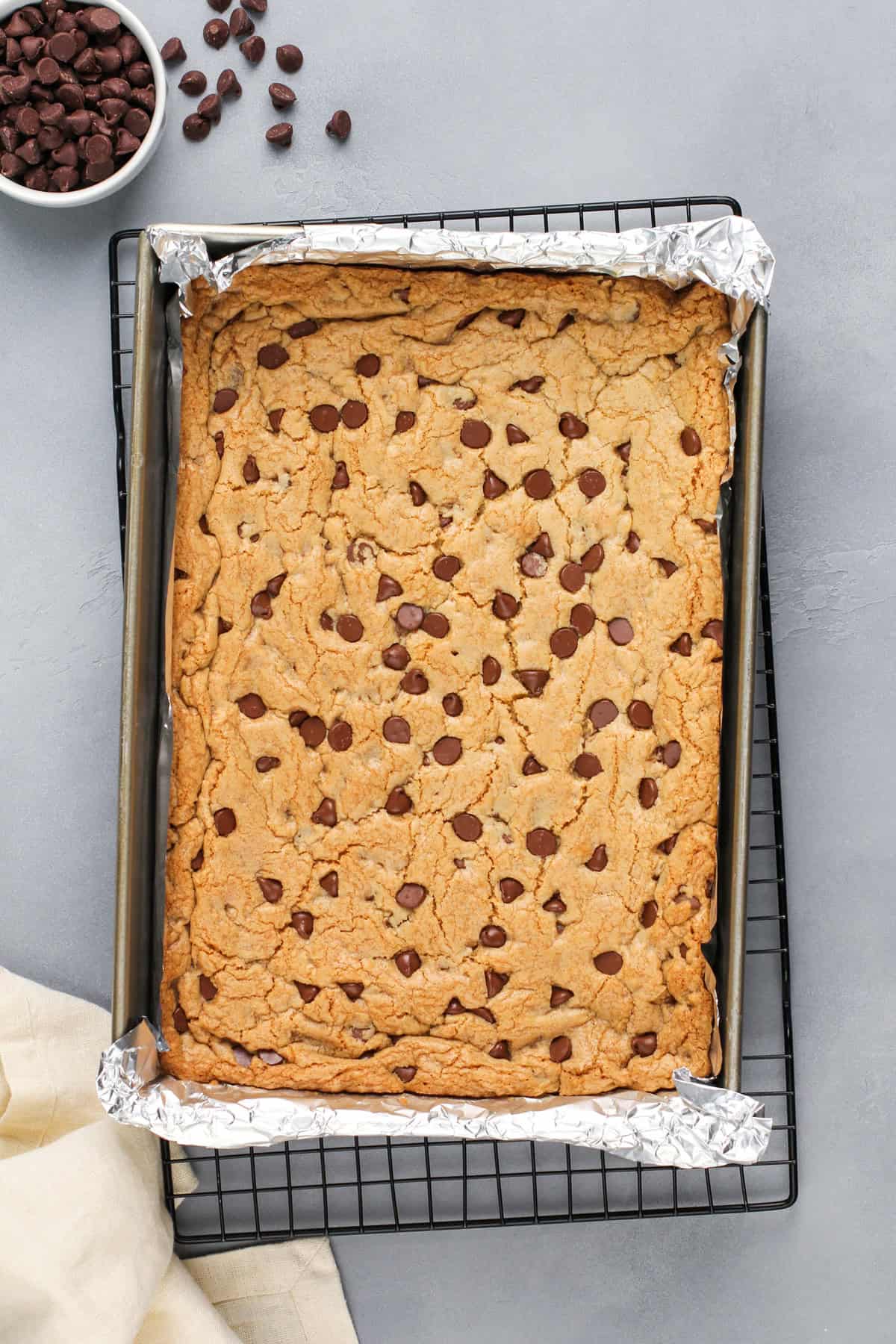 Baked chocolate chip cookie bars in a foil-lined pan.