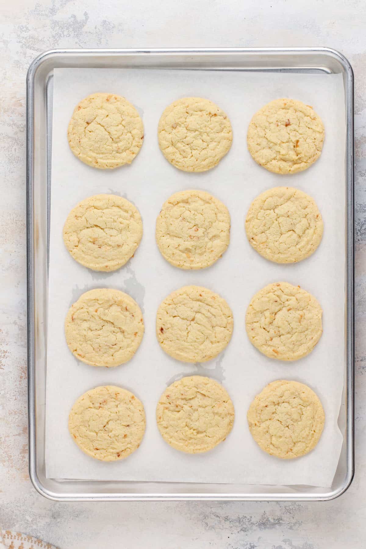 Baked coconut sugar cookies on a parchment-lined baking sheet.