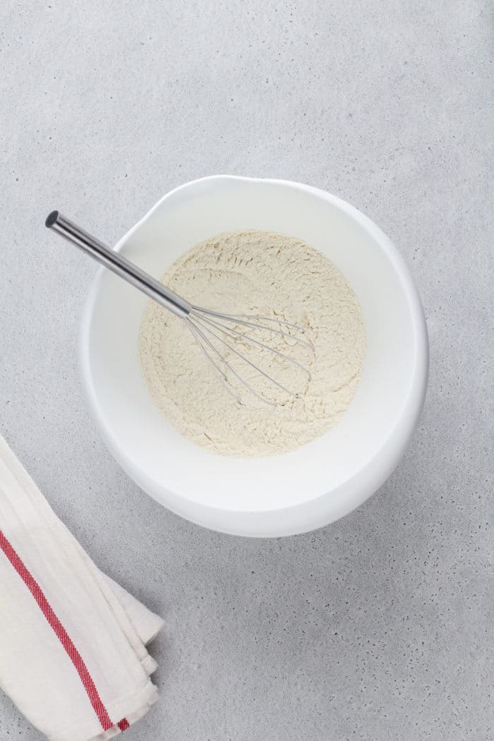 Dry ingredients for buttermilk drop biscuits being whisked together in a white bowl.