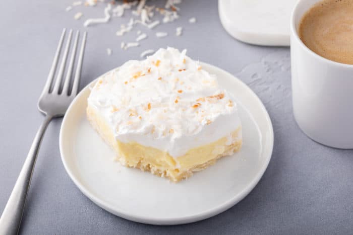 Coconut cream bar on a white plate. A bite has been taken from the corner of the bar.