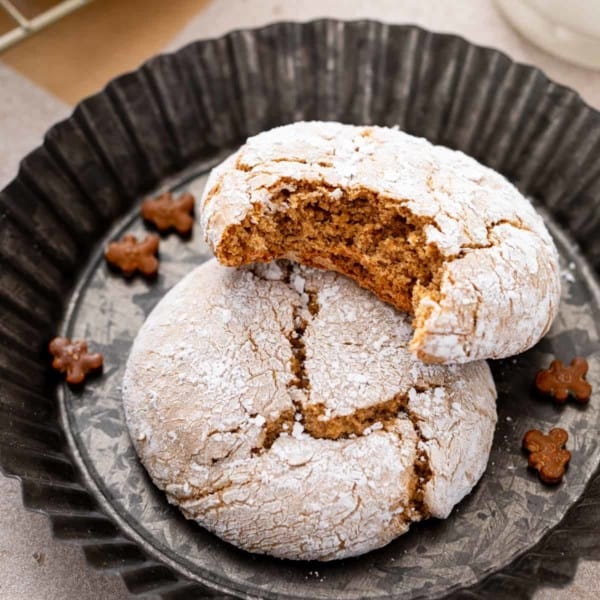 Two gingerbread crinkle cookies, one with a bite taken out of it.