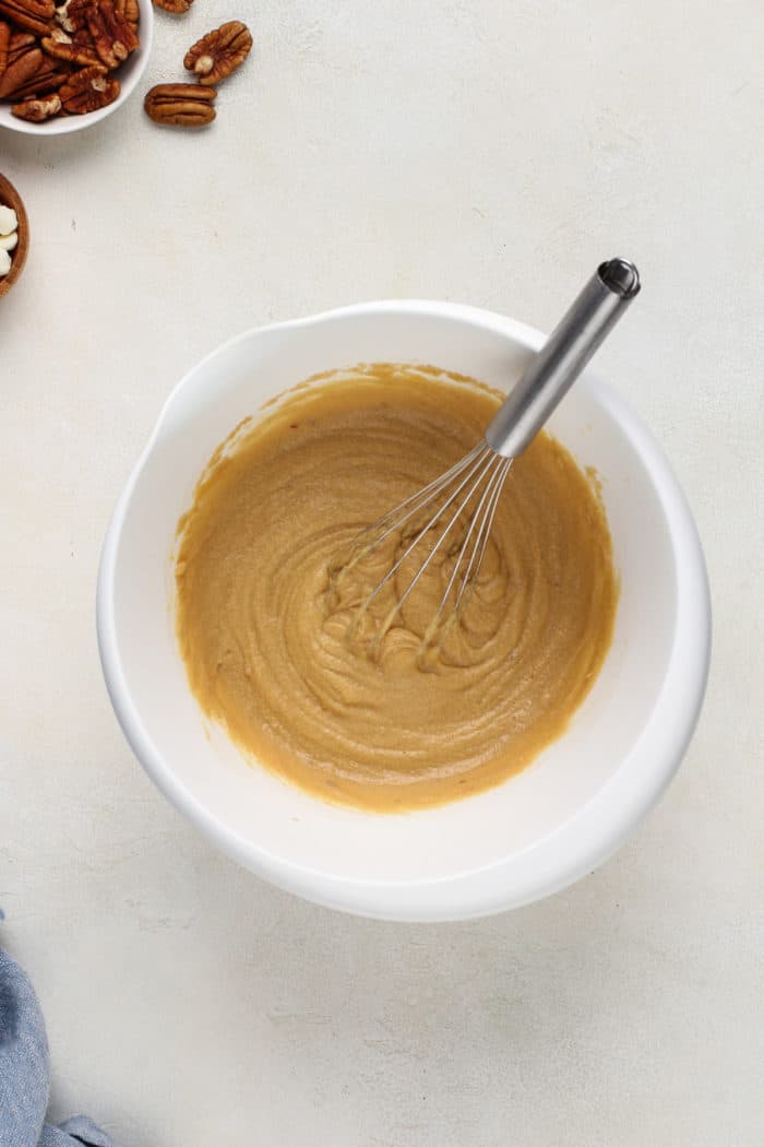 Wet ingredients for white chocolate pecan blondies mixed together in a white bowl.