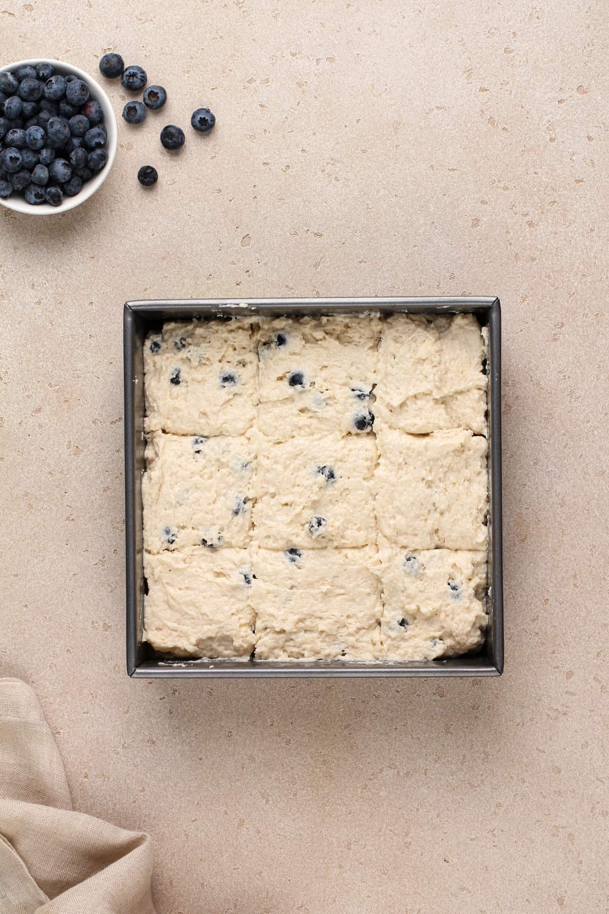 Unbaked blueberry biscuits in a metal pan, ready to go in the oven.