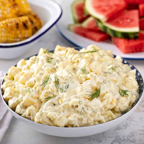 Serving bowl filled with easy potato salad garnished with sprigs of fresh dill.