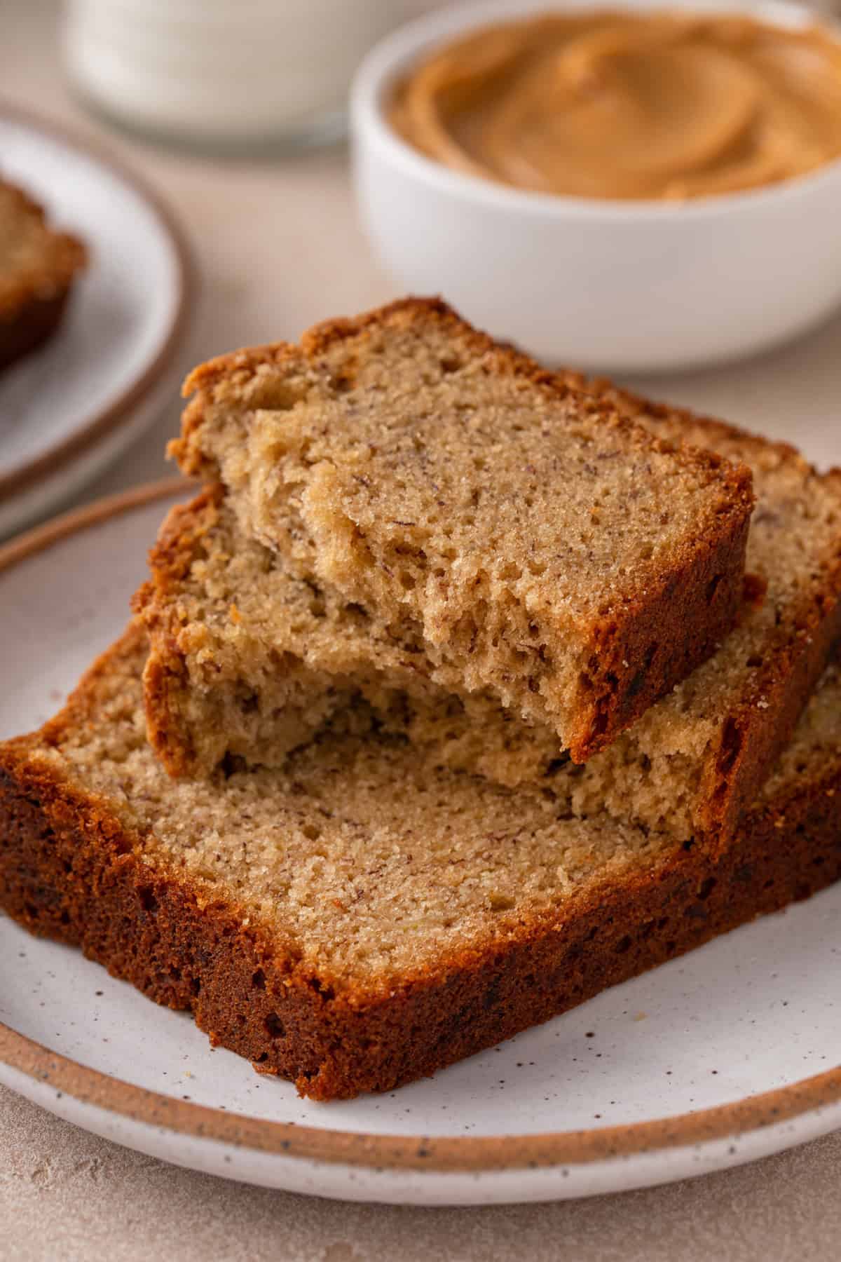 Slice of peanut butter banana bread broken in half, set on top of a second slice of bread.