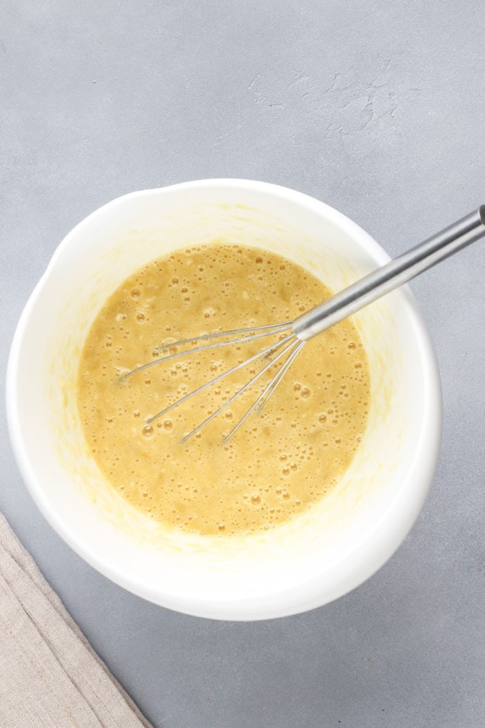 Wet ingredients for brown butter banana bread in a white mixing bowl.