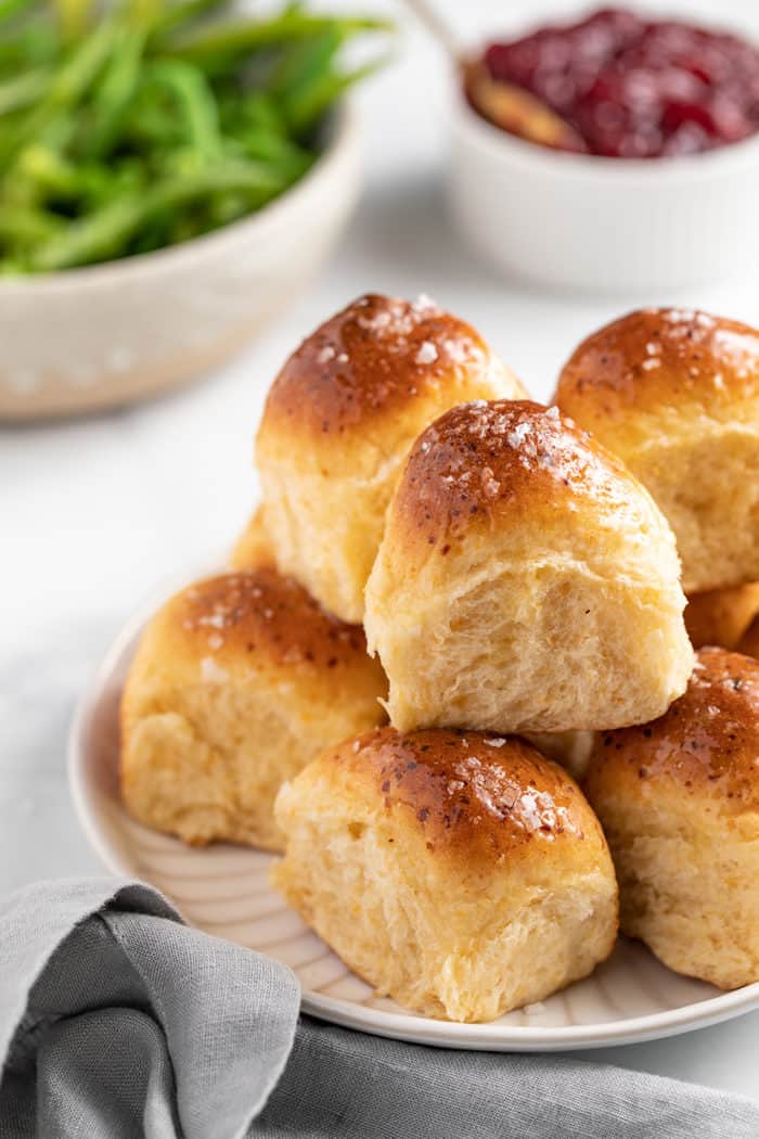 Cheddar dinner rolls piled on a white plate, set on a dinner table