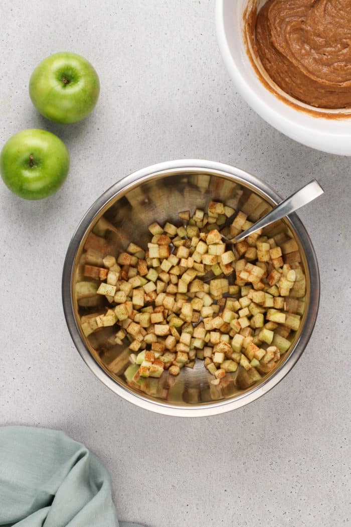 Cinnamon-coated apples in a metal bowl.