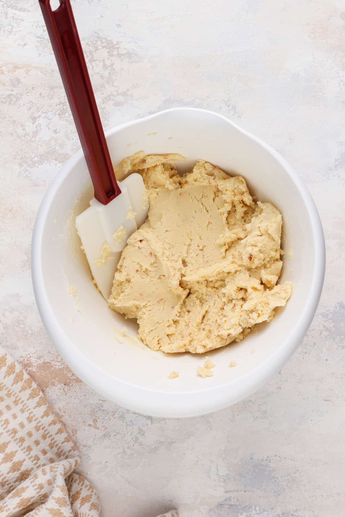 Coconut sugar cookie dough in a white mixing bowl.