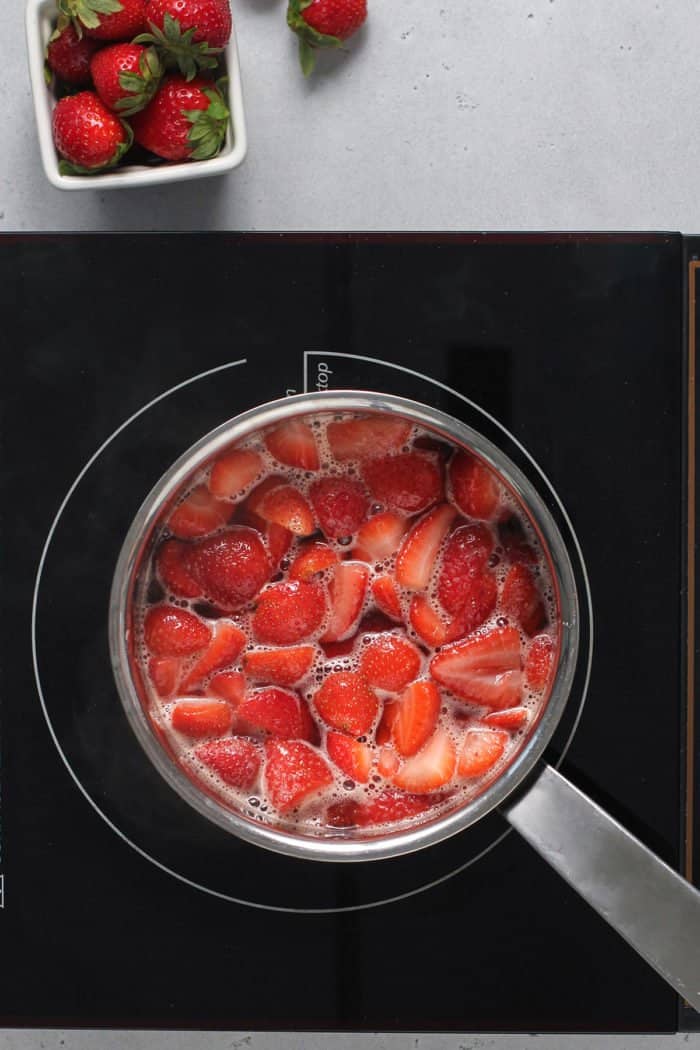 Strawberries cooking down in a metal saucepan