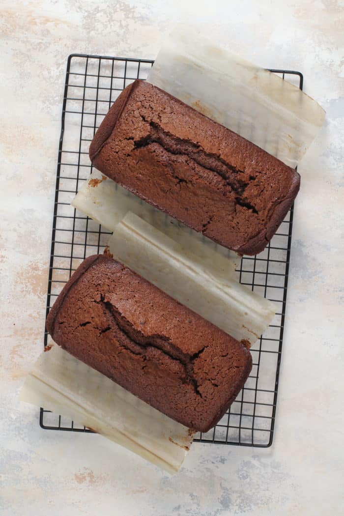 Two loaves of chocolate bread cooling on a wire rack.