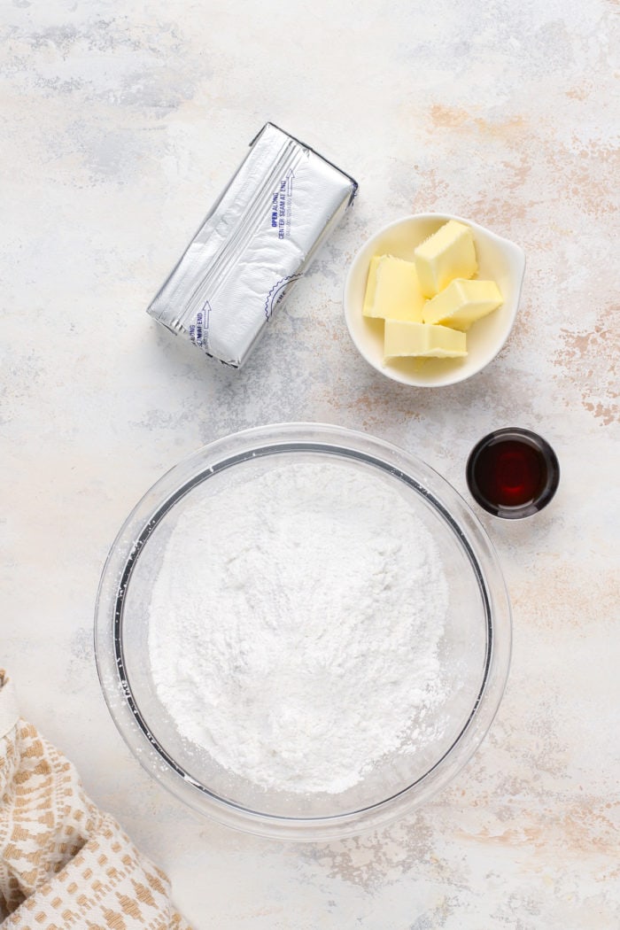 Bowl of cream cheese frosting next to a pan of cooled banana bars.