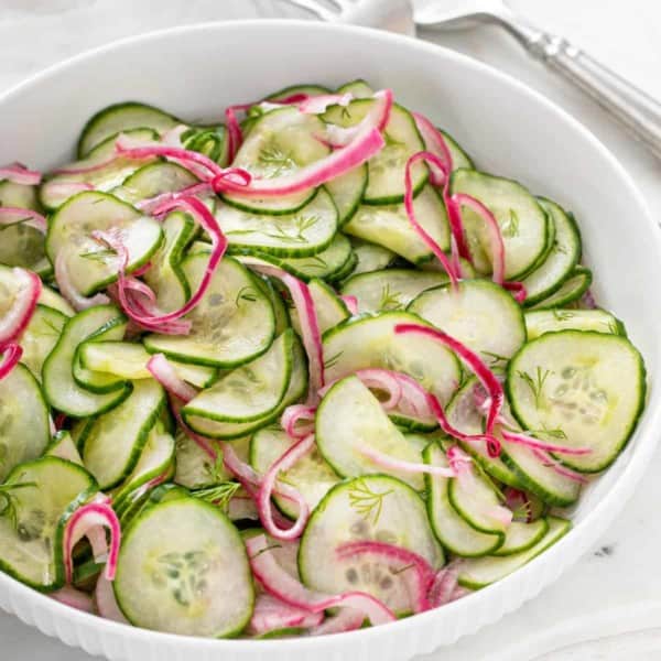 Large white serving bowl filled with cucumber salad.