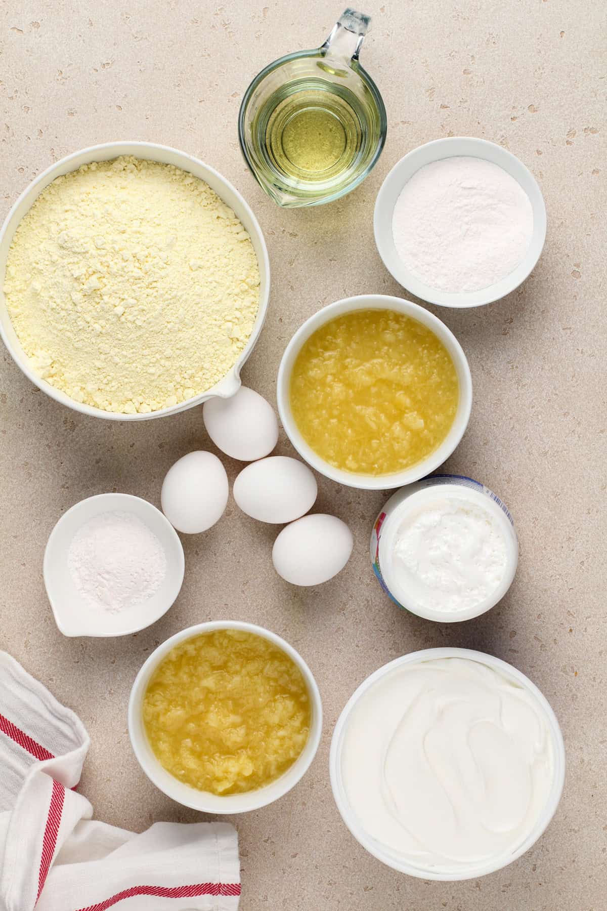 Ingredients for easy pineapple cake arranged on a beige countertop.