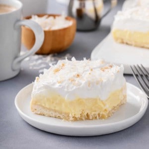 Coconut cream bar with a bite taken from the corner on a white plate.