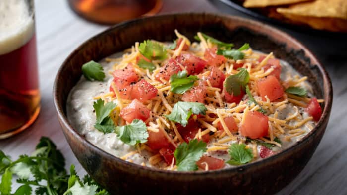 Avocado dip garnished with cheese, tomatoes, and cilantro.