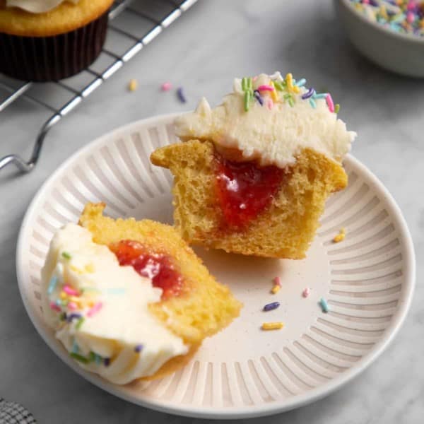 Filled cupcake cut in half on a white plate.