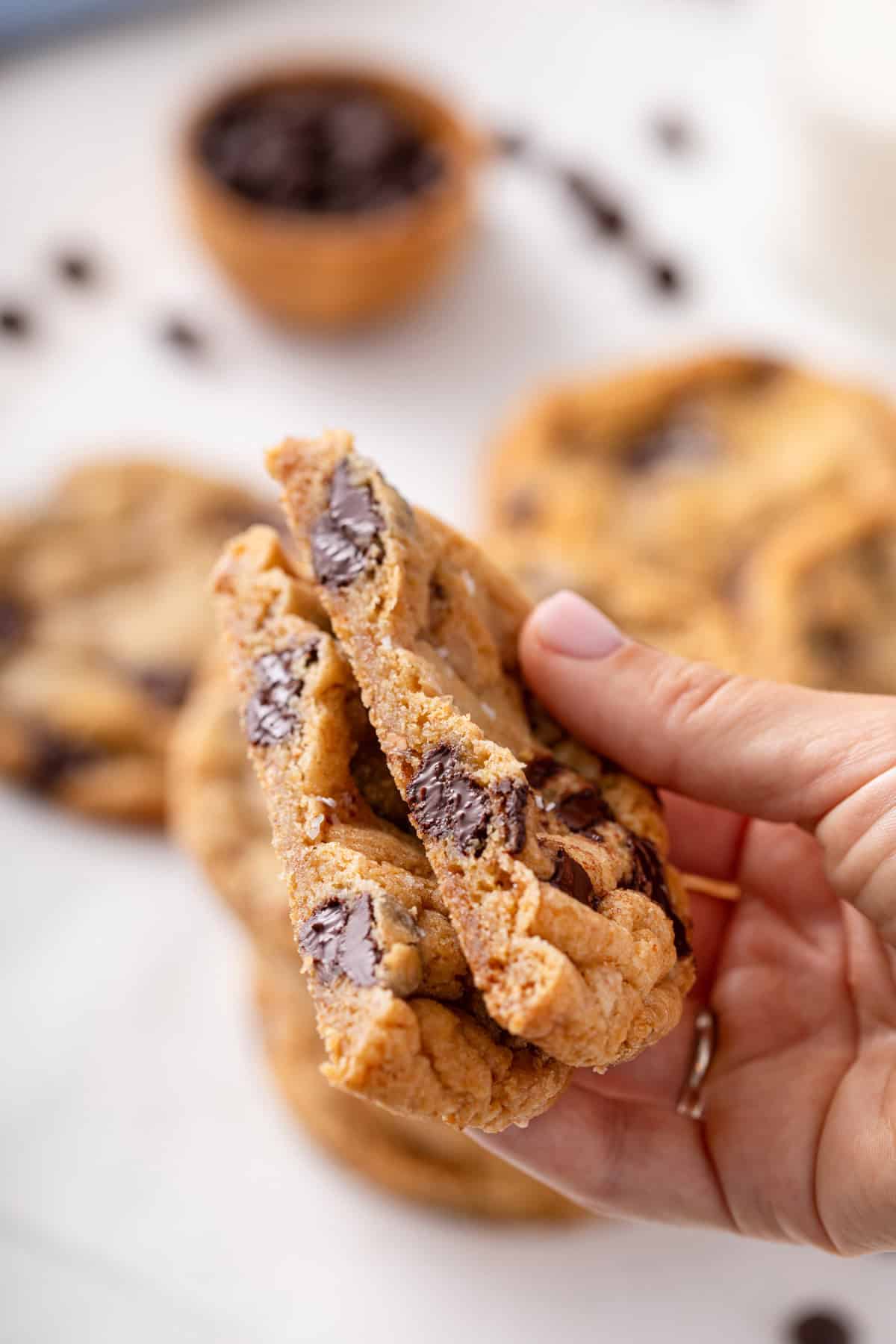 Handing holding up a halved heath bar cookie to show the inside texture.