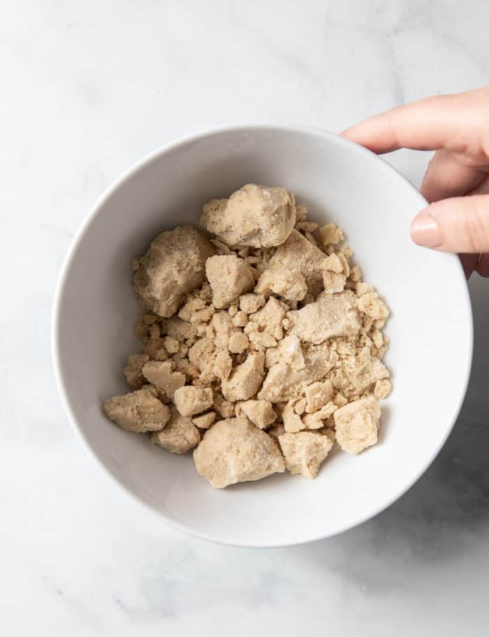 White bowl filled with hard clumps of brown sugar.