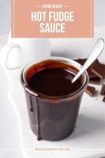 Spoon resting in a glass jar of hot fudge sauce set on a white board. Text overlay includes recipe name.