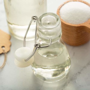 Glass bottle of simple syrup in front of a jar and a measuring cup of sugar