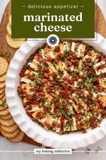 Overhead view of marinated cheese in a white serving dish on a platter surrounded by crackers. Text overlay includes recipe name.