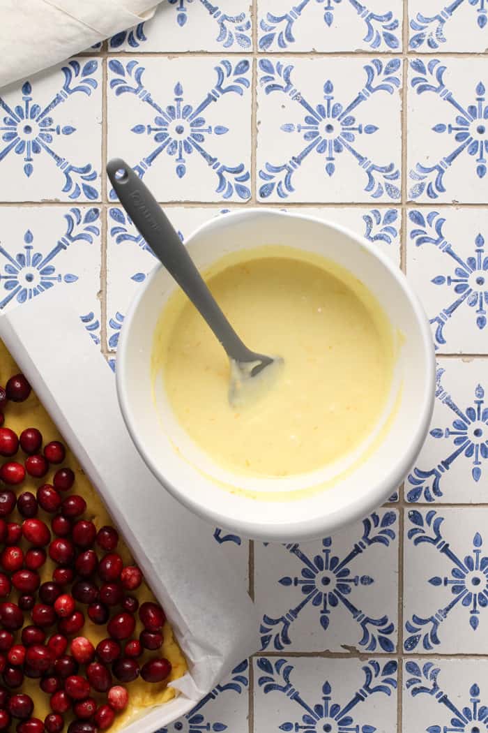 Spatula stirring together the cream cheese mixture for gooey butter bars in a white bowl