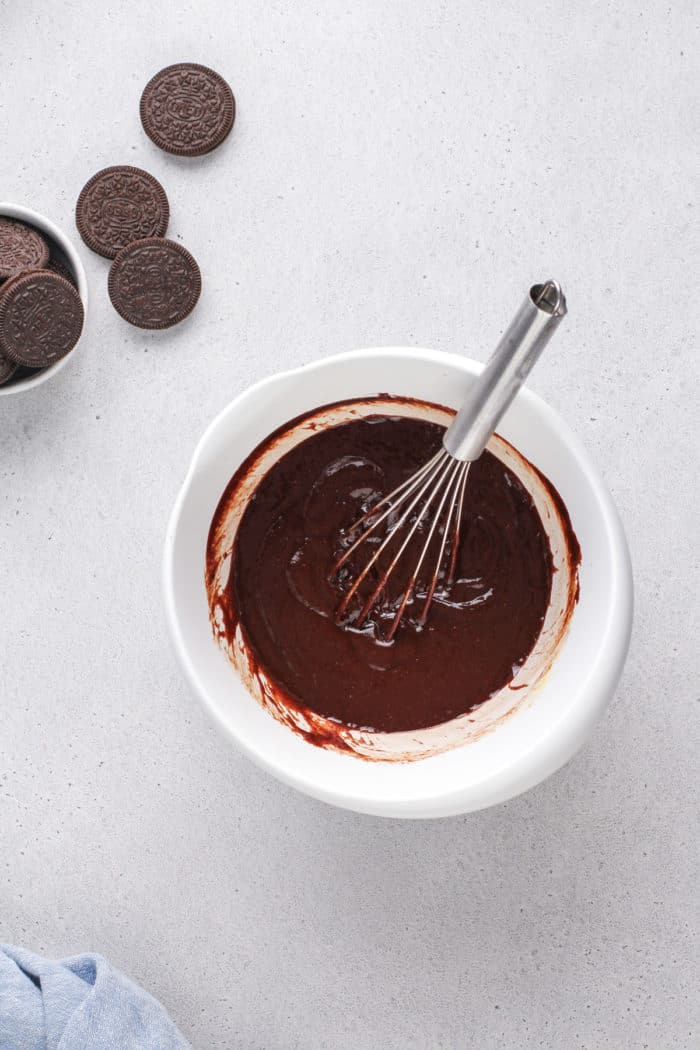 Brownie batter base being whisked together in a white mixing bowl.