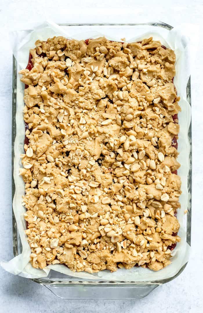 Peanut butter and jelly bars in a parchment-lined pan, ready to be baked