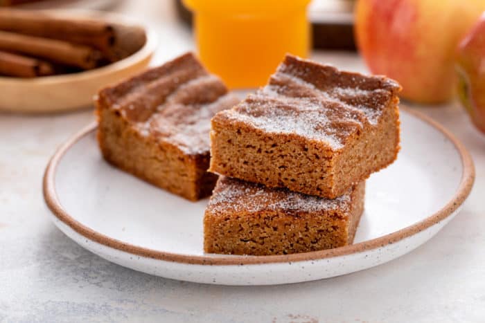 Three apple cider blondies arranged on a stoneware plate.