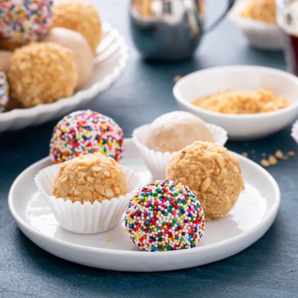 Assorted peanut butter balls on a white plate.