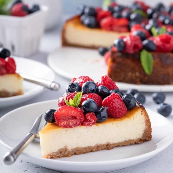 Plated slice of ricotta cheesecake, topped with raspberries and blueberries.