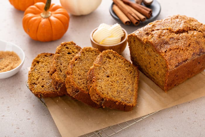 Sliced loaf of pumpkin banana bread on a wooden cutting board.