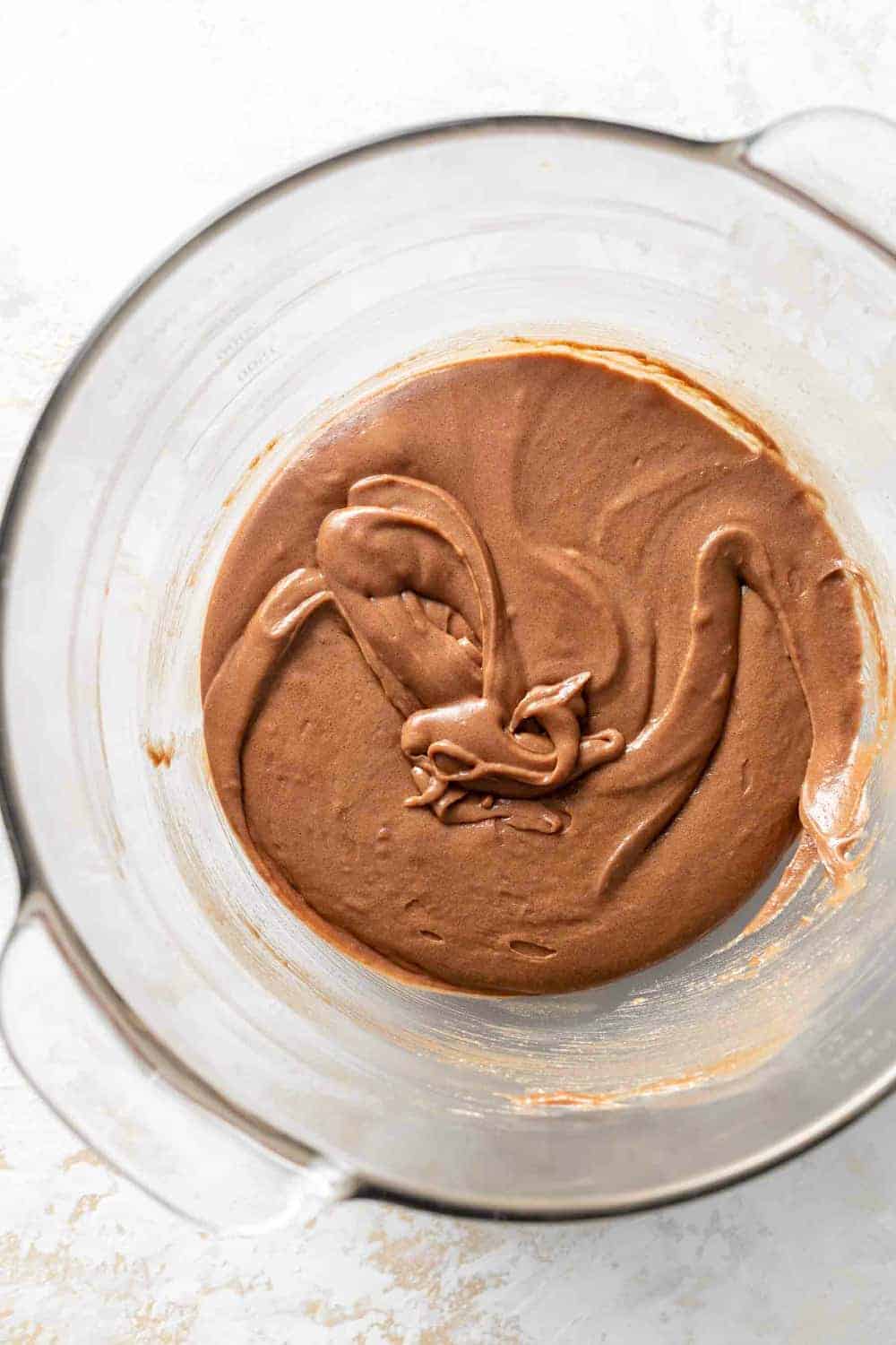 Brownie batter in a glass bowl, ready to be made into pumpkin brownies