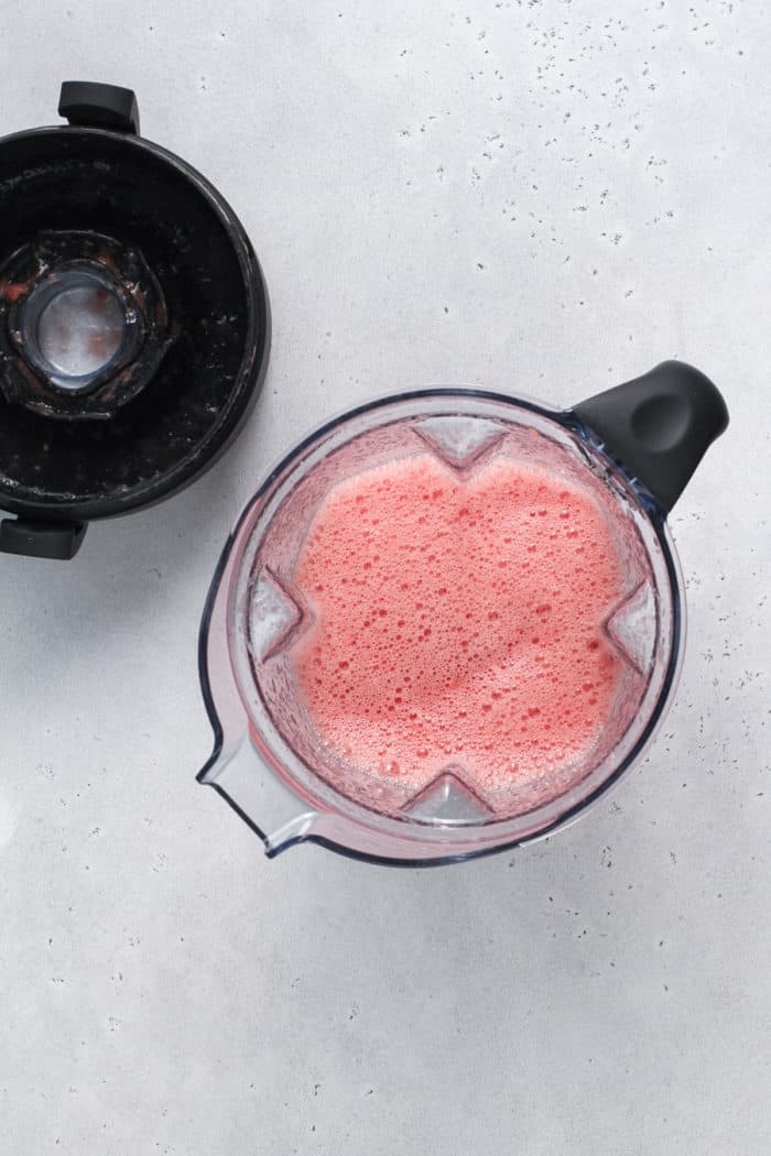 Pureed watermelon in the pitcher of a blender, set on a countertop.