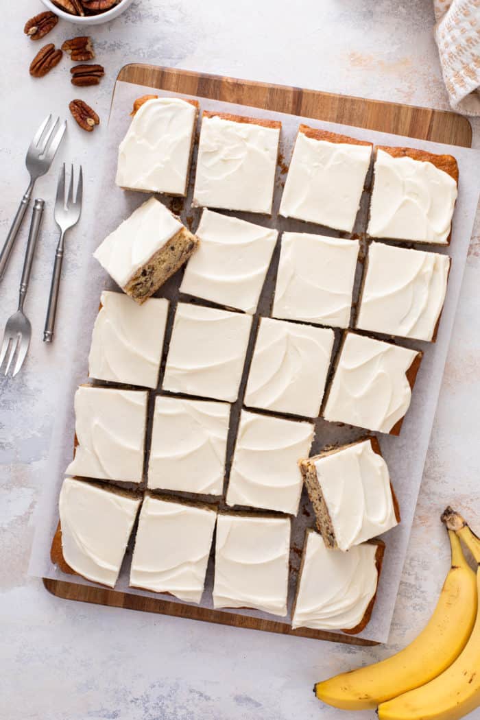 Sliced pan of banana bars topped with cream cheese frosting.