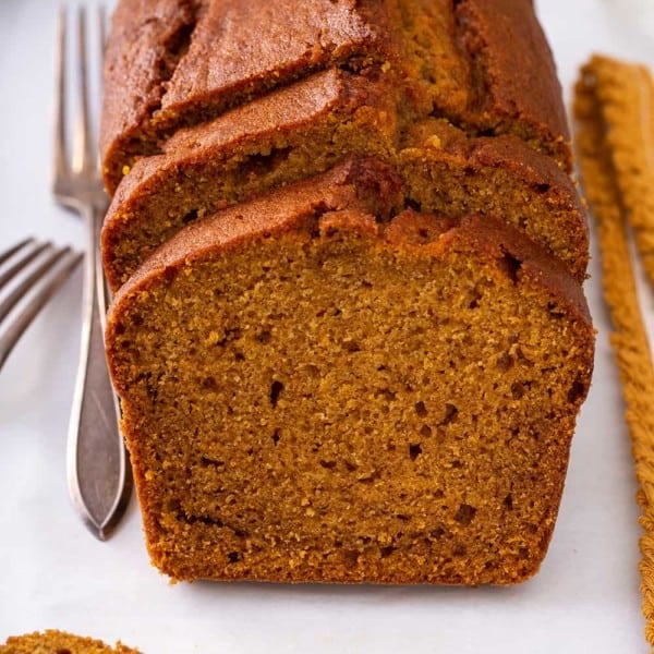 Sliced loaf of pumpkin bread on a white cutting board