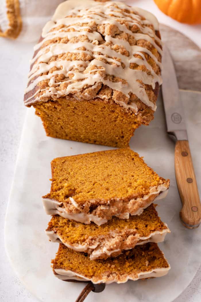 Sliced loaf of streusel-topped pumpkin bread with maple glaze.