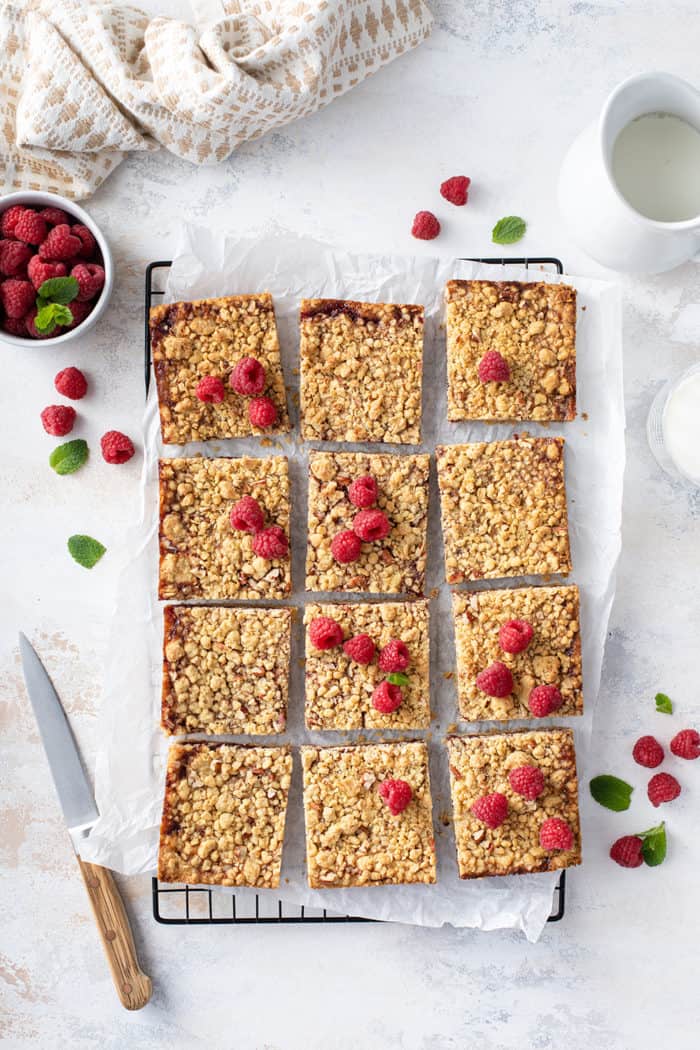 Overhead view of raspberry bars sliced into 12 bars, garnished with fresh raspberries