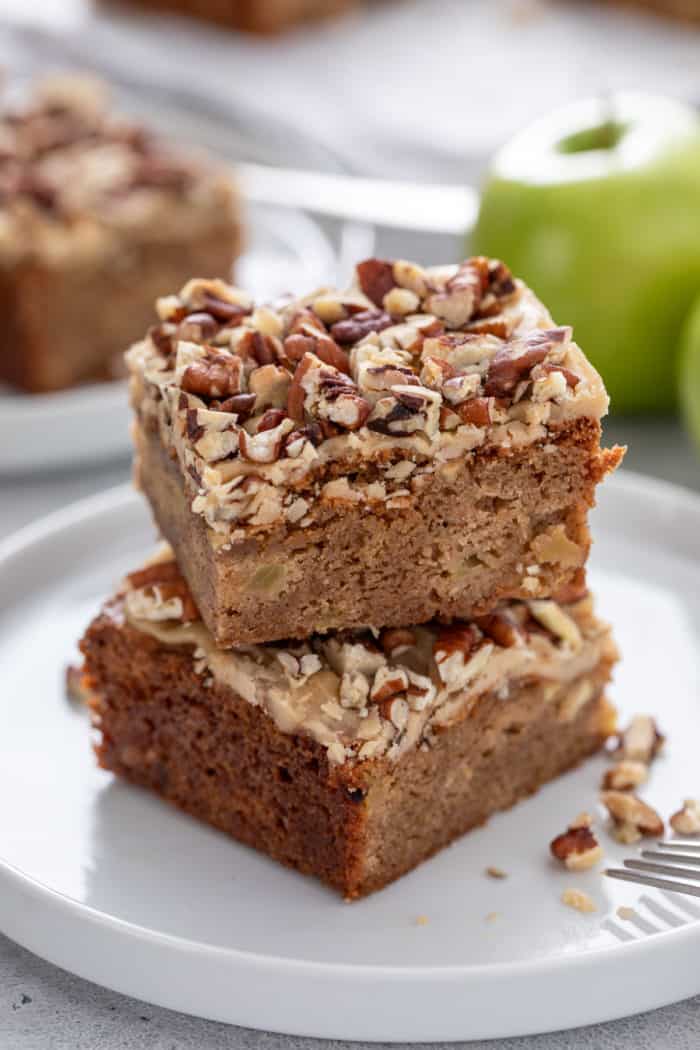 Two caramel apple blondies stacked on a white plate.