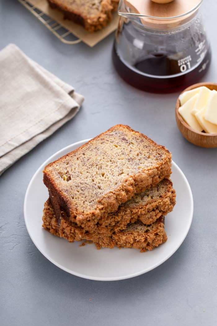 Three slices of brown butter banana bread stacked on a white plate.