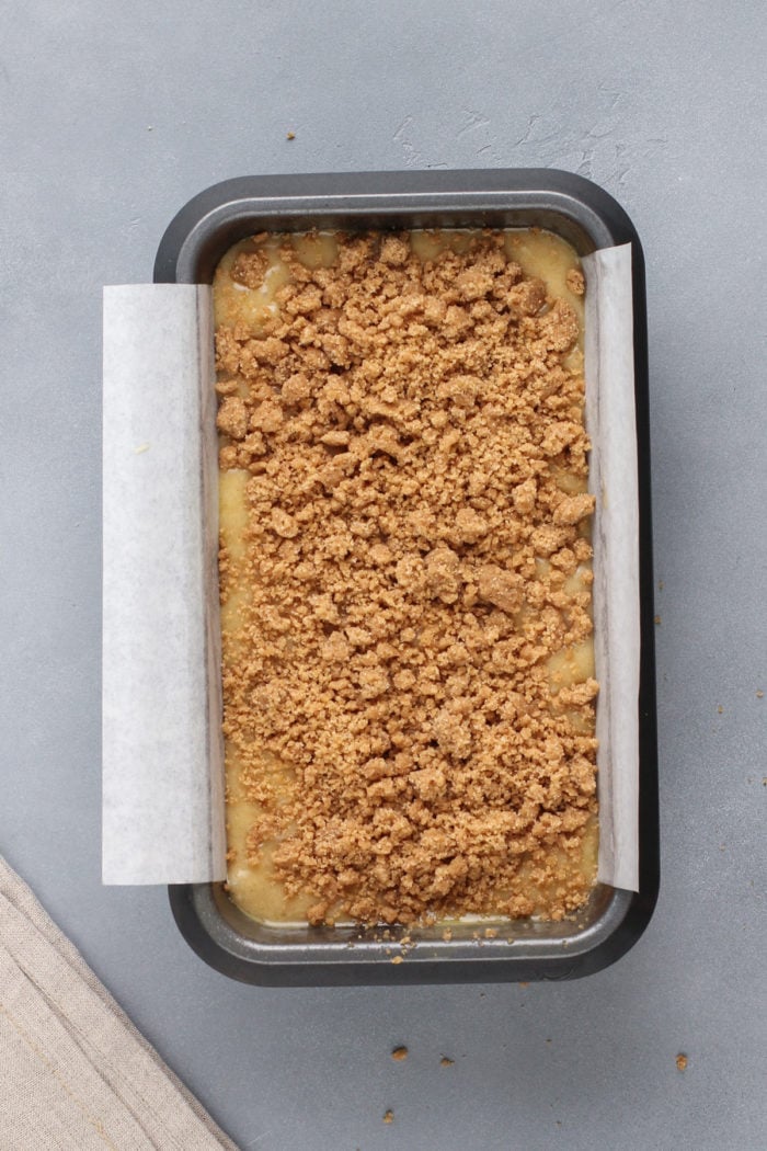 Unbaked brown butter banana bread in a loaf pan, topped with streusel, ready to bake in the oven.