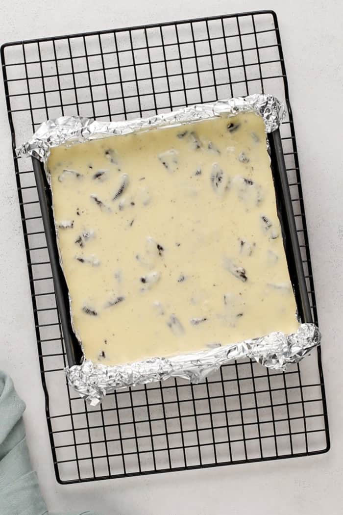 Unbaked oreo cheesecake bars in a foil-lined pan, ready to go in the oven.