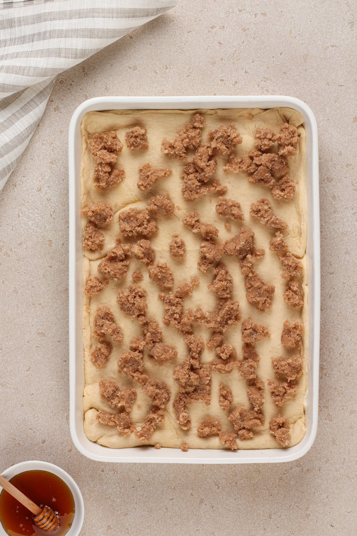 Assembled and unbaked sopapilla cheesecake in a white pan, ready to go in the oven.