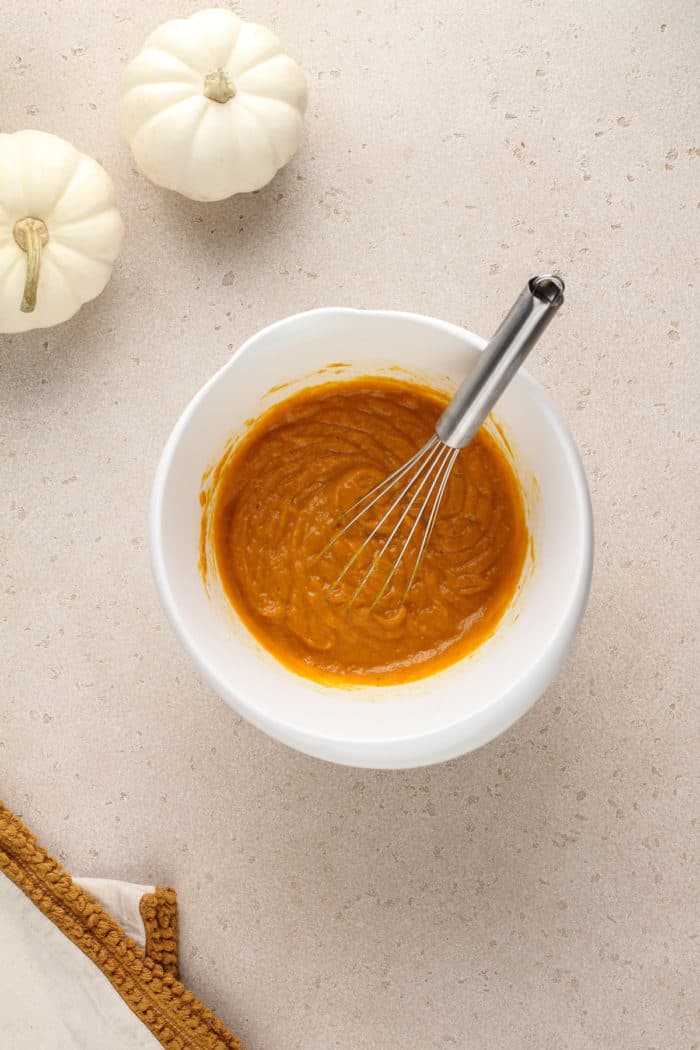 Wet ingredients for brown butter pumpkin bread in a white mixing bowl.